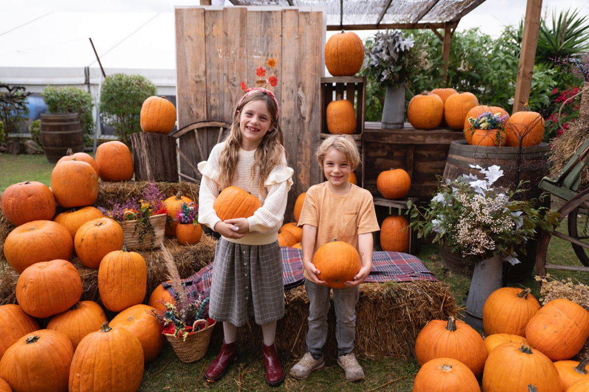 Two children holding pumpkins in the pumpkin field in Sitges